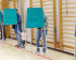 Voters standing inside green fabric voting booths lined up in a gymnasium.